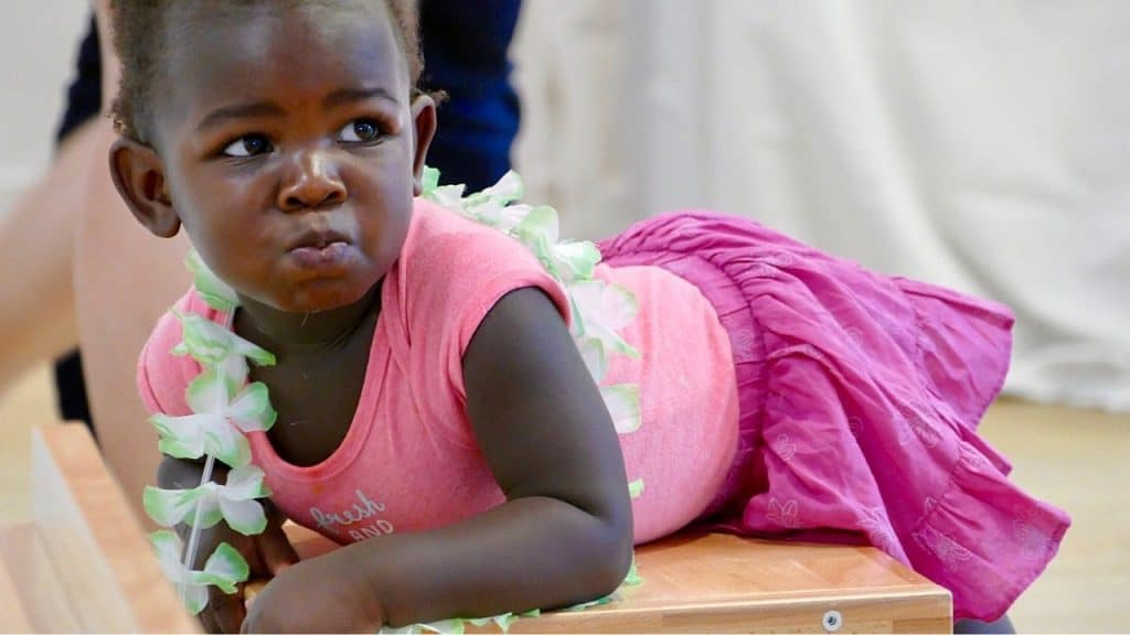 un bébé en jupe rose allongé sur un siege de la crèche claudine olivier à paris